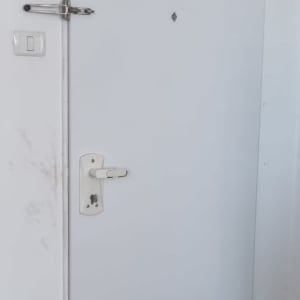 דלת לבנה עם מנעול ובריח מתכת