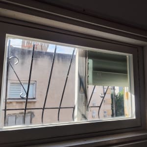 חלון זכוכית עם סורגי מתכת ותריס פתוח