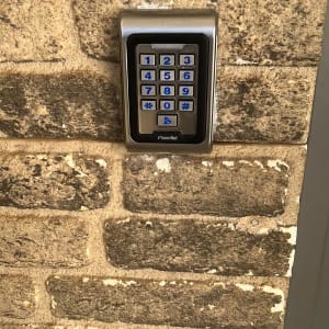 מערכת אינטרקום מותקנת על קיר לבנים עם לוח מקשים.