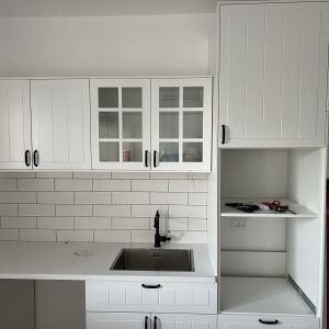 ארונות מטבח לבנים עם ידיות שחורות וכיור נירוסטה