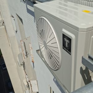 יחידת מיזוג אוויר מותקנת על קיר חיצוני של בניין.