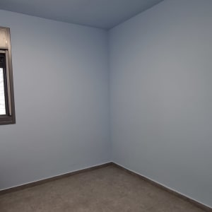 חדר צבוע בצבע כחול בהיר עם רצפת אריחים אפורה