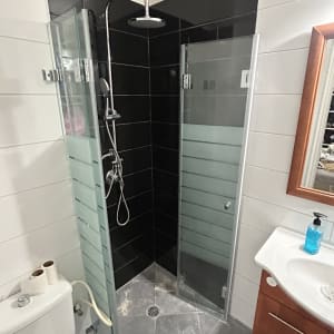 מקלחון זכוכית עם ראש מקלחת וכיור בחדר אמבטיה