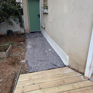 שביל עץ ליד קיר עם דלת ירוקה