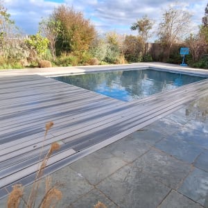 בריכת שחייה עם דק עץ וסביבה צמחייה ירוקה