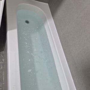 אמבטיה עם מים וראש מקלחת על קיר אריחים