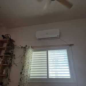 מזגן תלוי על קיר מעל חלון עם וילון