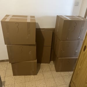 קופסאות קרטון מסודרות על רצפה ליד ארון עץ