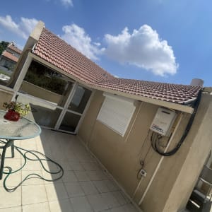 גג רעפים אדום עם שמיים כחולים ועננים