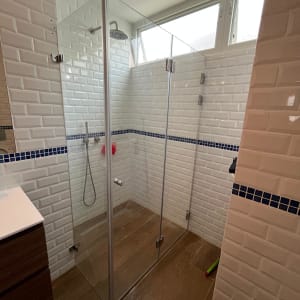 מקלחון זכוכית עם אריחים לבנים וראש מקלחת