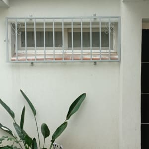 חלון עם סורגים מעוצבים על קיר לבן