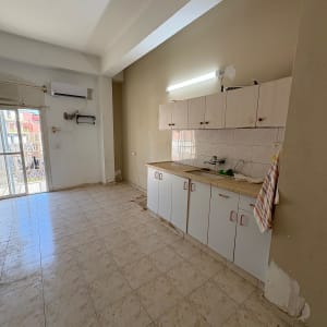 מטבח ריק עם ארונות לבנים וקיר צבוע