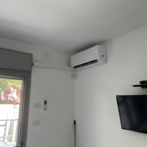 מזגן מותקן על קיר ליד חלון וטלוויזיה