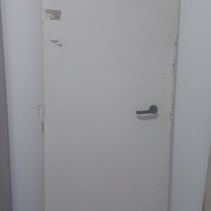 דלת עם ידית שחורה על רקע קיר לבן