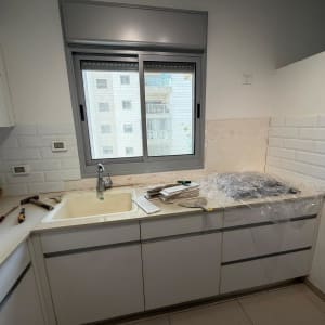 חיפוי קיר מטבח באריחי בריקים לבנים במהלך עבודת שיפוץ