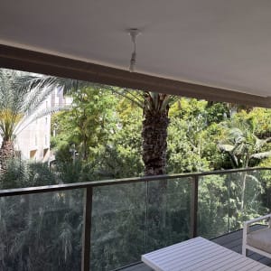 מרפסת עם סוכך חום סגור מעל מעקה זכוכית.