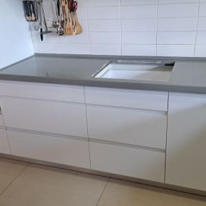 מטבח עם ארונות לבנים ומשטח עבודה אפור