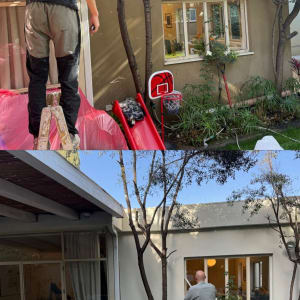 אדם צובע קיר חיצוני של בית עם עצים מסביב