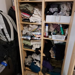 ארון בגדים עם מדפים מבולגנים, בגדים מקופלים ומוצרי טיפוח