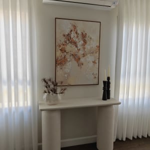 שולחן עם עציץ, תמונה ומזגן על הקיר