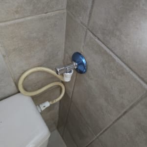 חיבור צינור למיכל שירותים על קיר אריחים