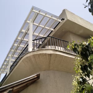 מרפסת עם פרגולה לבנה וצמחייה ירוקה