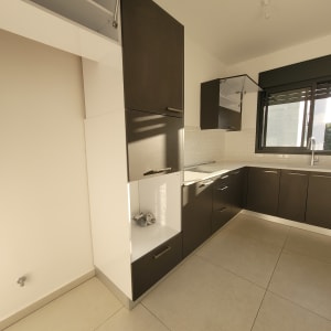 מטבח נקי עם ארונות כהים ורצפת אריחים בהירה