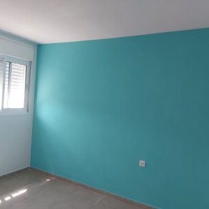 קיר צבוע בכחול בהיר עם חלון בצד