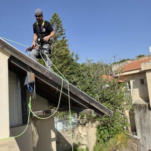 אדם על גג עם ציוד בטיחות וחבלים