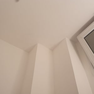 קיר לבן עם חלון קטן בפינה