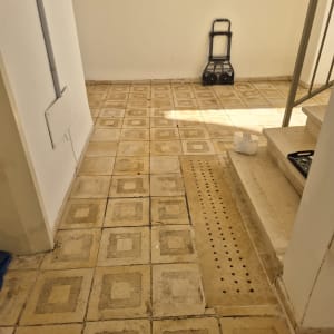 רצפה מרוצפת עם דלי קטן ליד מדרגות