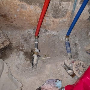 צינורות מים אדומים וכחולים על קיר בטון