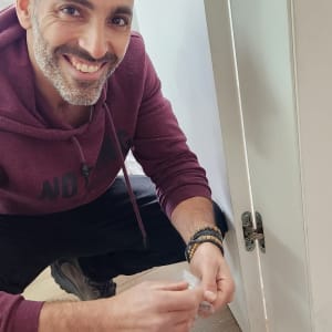 אדם מתקין ציר לדלת לבנה