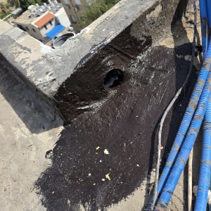 עבודת איטום ביטומני בראש גג בניין בגובה