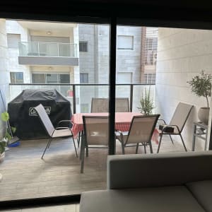 מרפסת עם שולחן וכיסאות מאחורי דלת זכוכית