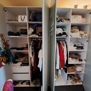 ארון בגדים פתוח עם מדפים מלאים בבגדים מקופלים ותלויים