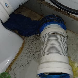 צינור פלסטיק לבן עם חיבורים כחולים על רצפת חדר אמבטיה