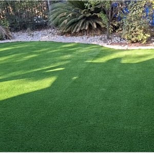 התקנת דשא סינטטי בגינה פרטית עם תיחום אבנים דקורטיביות וצמחייה