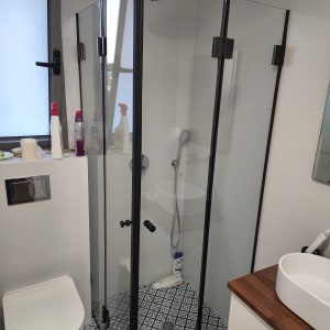 מקלחון זכוכית עם ראש מקלחת ומוצרי ניקוי