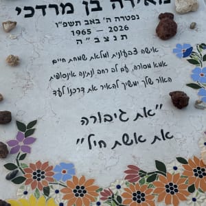 מצבה מעוטרת בפרחים צבעוניים ואבנים קטנות