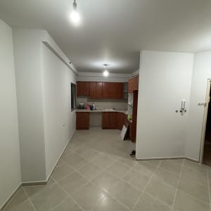 מטבח עם ארונות עץ, מנורות תלויות, קיר לבן