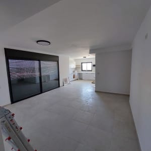 סולם מתכת מתקפל בחדר ריק עם חלון גדול