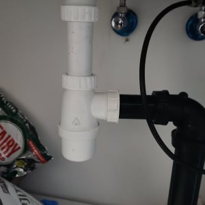 צנרת מתחת לכיור עם חיבורים לבנים ושחורים