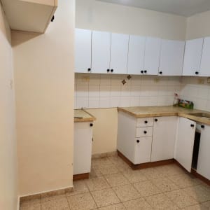 מטבח נקי עם ארונות לבנים ורצפה נקייה