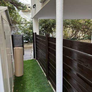 גדר צבועה בצבע כהה ליד דשא סינתטי