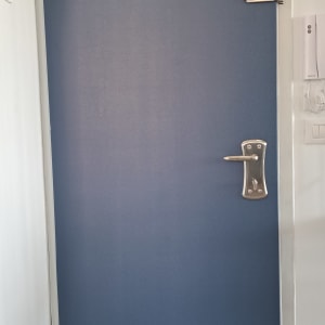 דלת כחולה עם ידית מתכת ובריח עליון