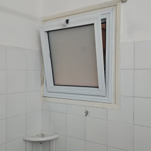 חלון אלומיניום פתוח בחדר אמבטיה עם אריחים לבנים