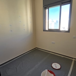 חדר עם דלי צבע ומכסה על הרצפה