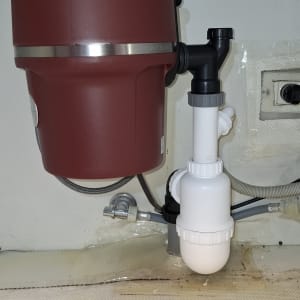 מטחנת אשפה מתחת לכיור עם צינורות חיבור