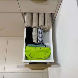 מגבות מגולגלות ומיכל ירוק במגירה פתוחה